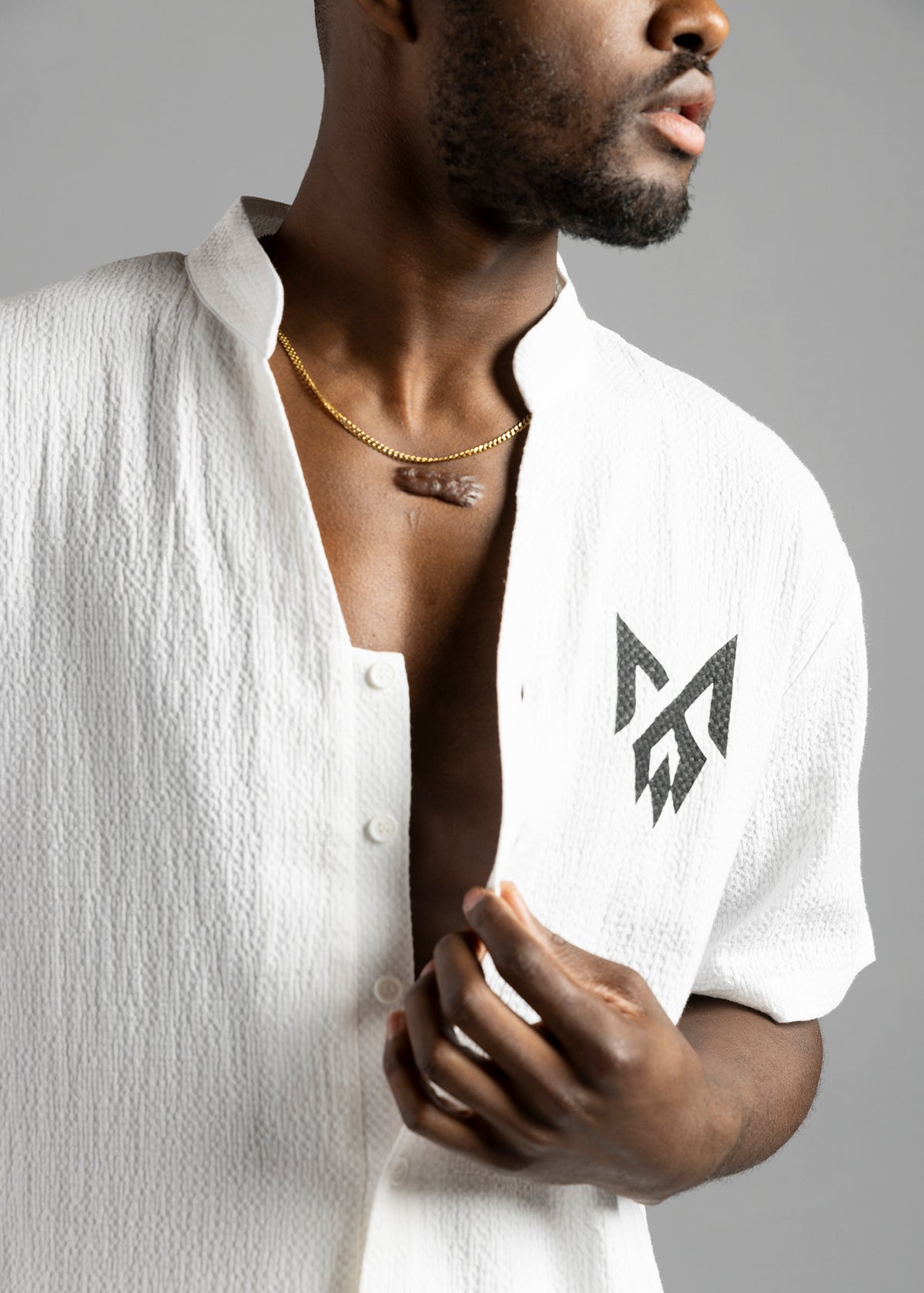 Front close-up of the white MW Button Up Jumpsuit by MilkWhite, showing the collar, buttons and black chest logo.