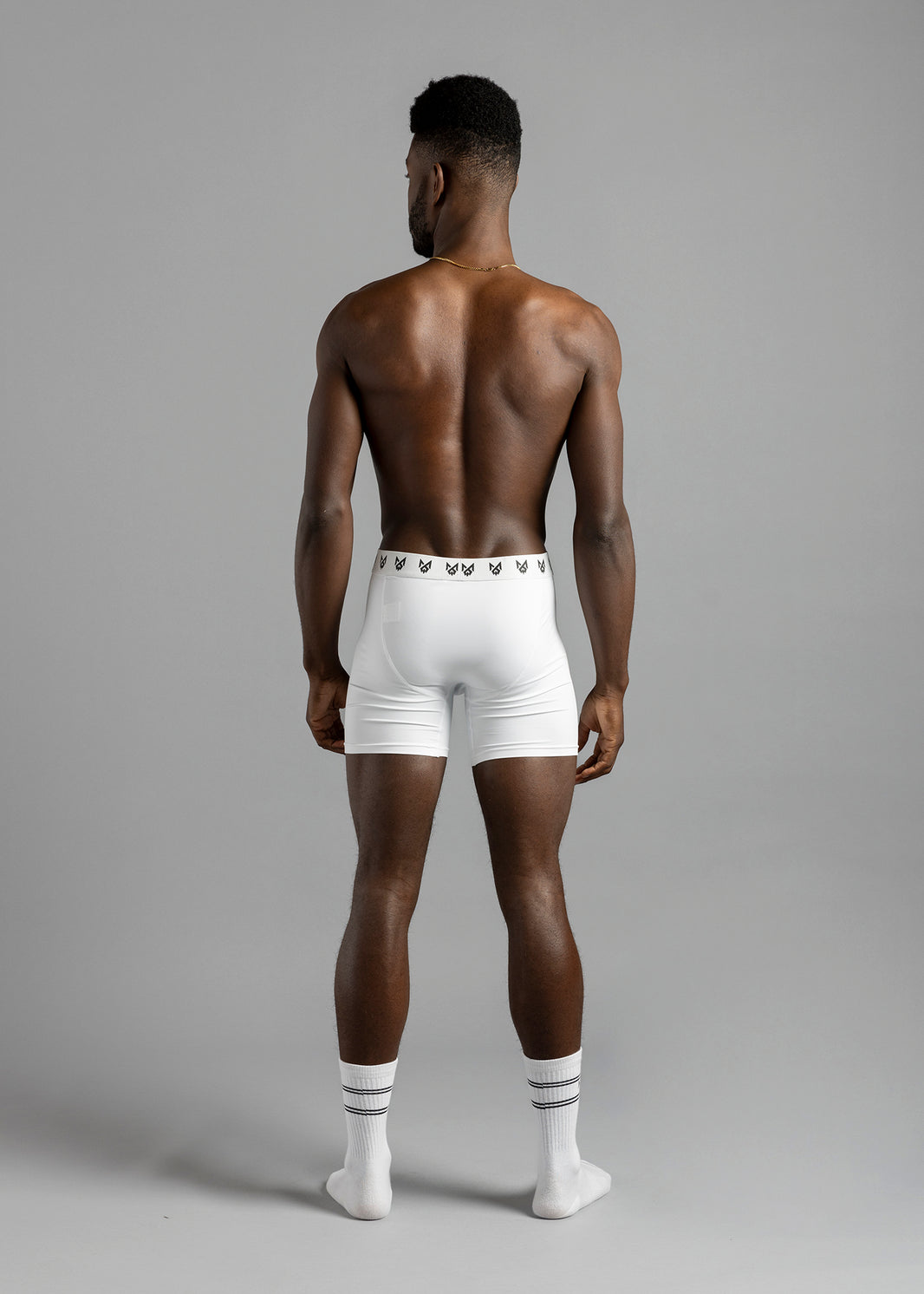 Full-length rear view of a model wearing white MilkWhite Boxer Brief Underwear, showing the logo waistband and leg hems.