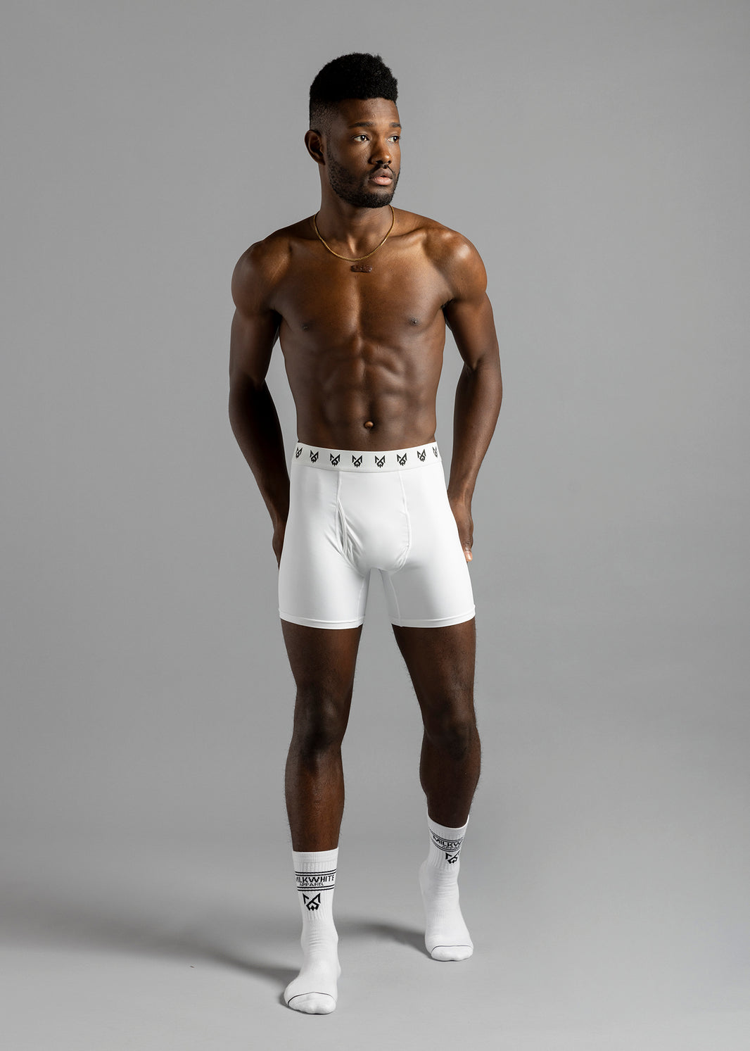 Full-length front view of a model wearing white MilkWhite Boxer Brief Underwear with a repeating black logo waistband.