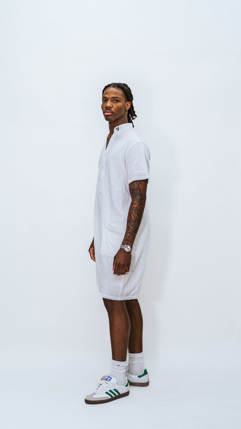 Front sideview of model wearing Milkwhite white button down jumpsuit showing from side progile and logo on collar.