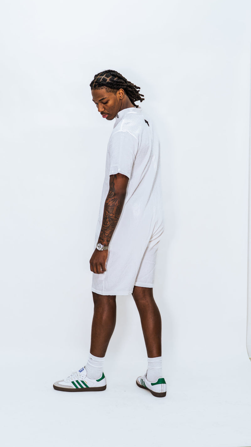 Rear sideview of model wearing the Milkwhite white button down jumpsuit on a white background.