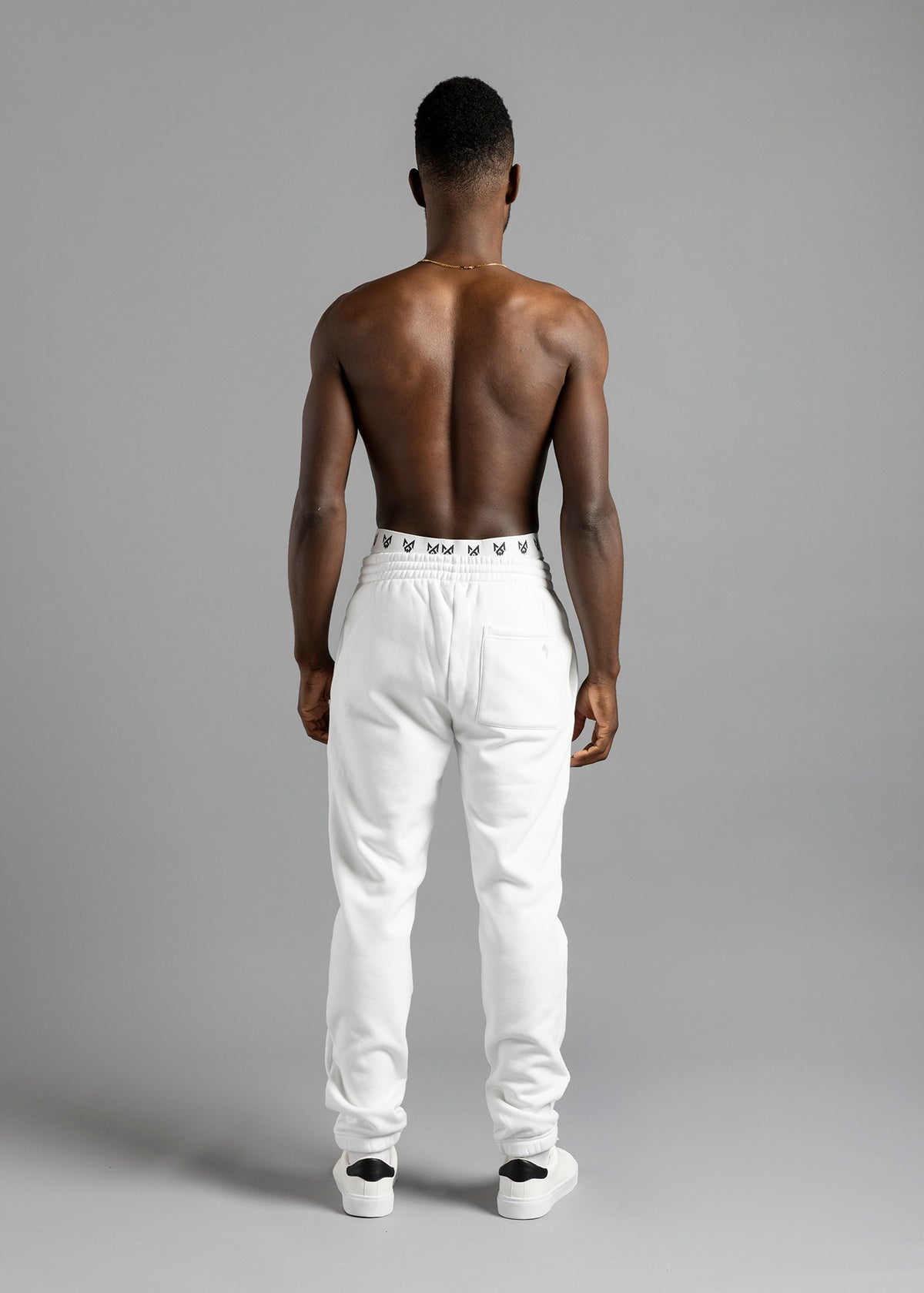 Full-length rear view of a model wearing white MilkWhite Comfortable Joggers, showing the gathered waist, back patch pocket and ankle cuffs.