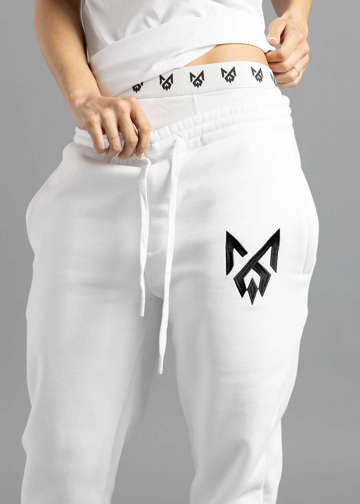 Front close-up of white MilkWhite Comfortable Joggers, showing the gathered drawstring waistband and black logo on the thigh.