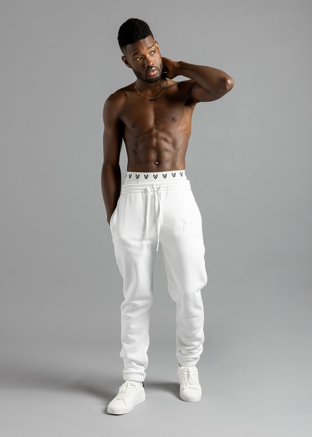 Full-length front view of a model wearing white MilkWhite Comfortable Joggers, with one hand behind the neck and the other in a side pocket.