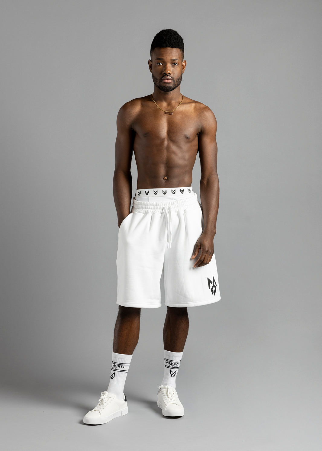 Full-length front view of a model wearing MilkWhite Jogger Shorts, with a drawstring waist and black logo on the leg.