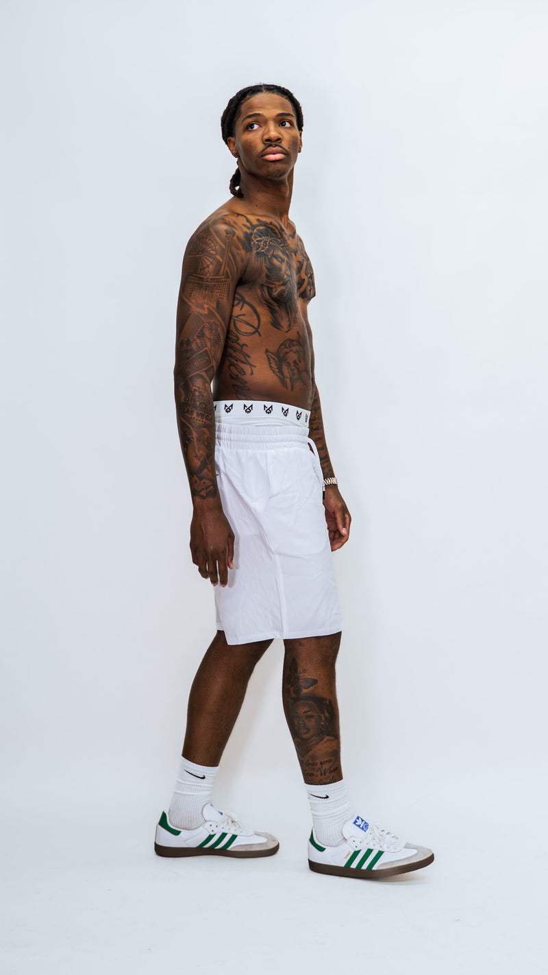 Full-length side view of a model wearing white MilkWhite Long Swim Trunks, showing the side pocket and straight leg hem.