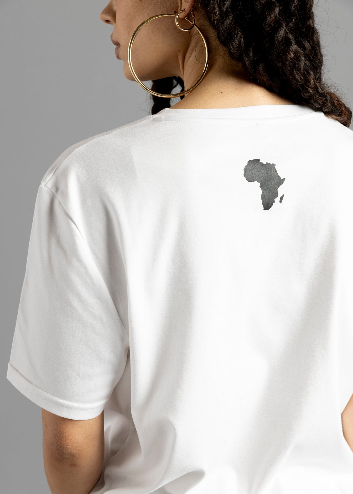 Rear close-up of the white MilkWhite Premium T-Shirt, showing a dark Africa-shaped graphic below the neckline and the short sleeve hem.