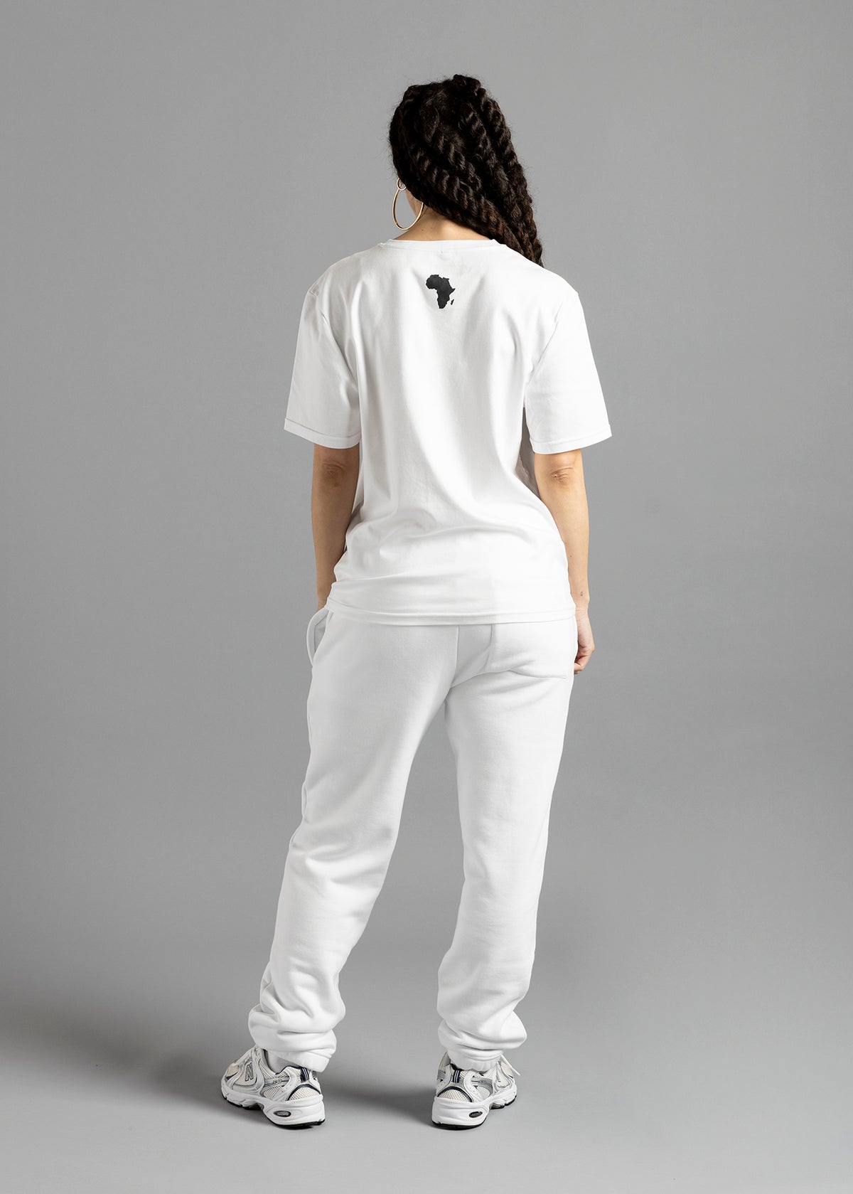 Full-length rear view of a model wearing the white MilkWhite Premium T-Shirt, showing short sleeves and a dark Africa-shaped graphic on the upper back.