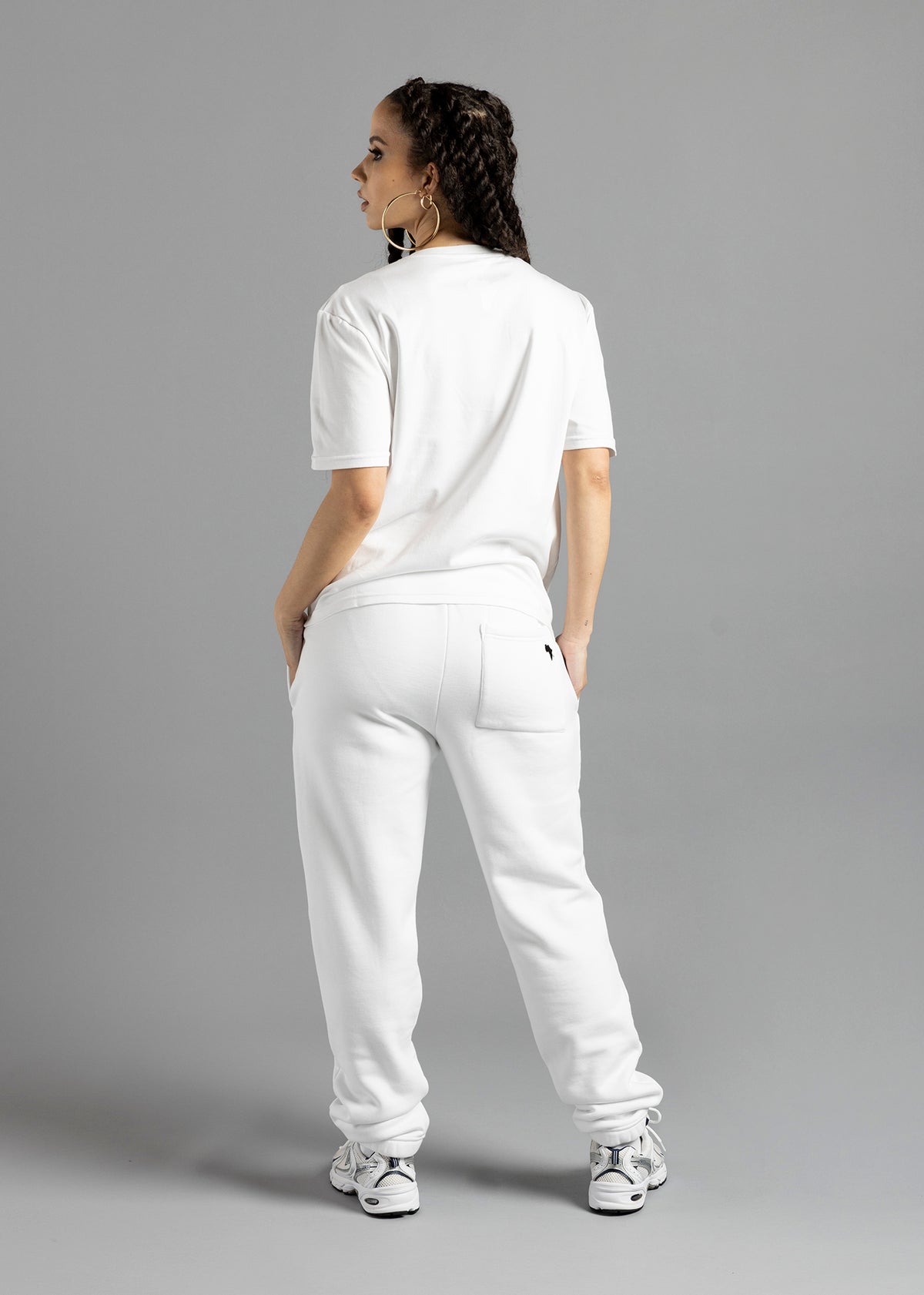 Full-length rear three-quarter view of a model wearing the white MilkWhite Premium T-Shirt, showing its short sleeves and straight hem.