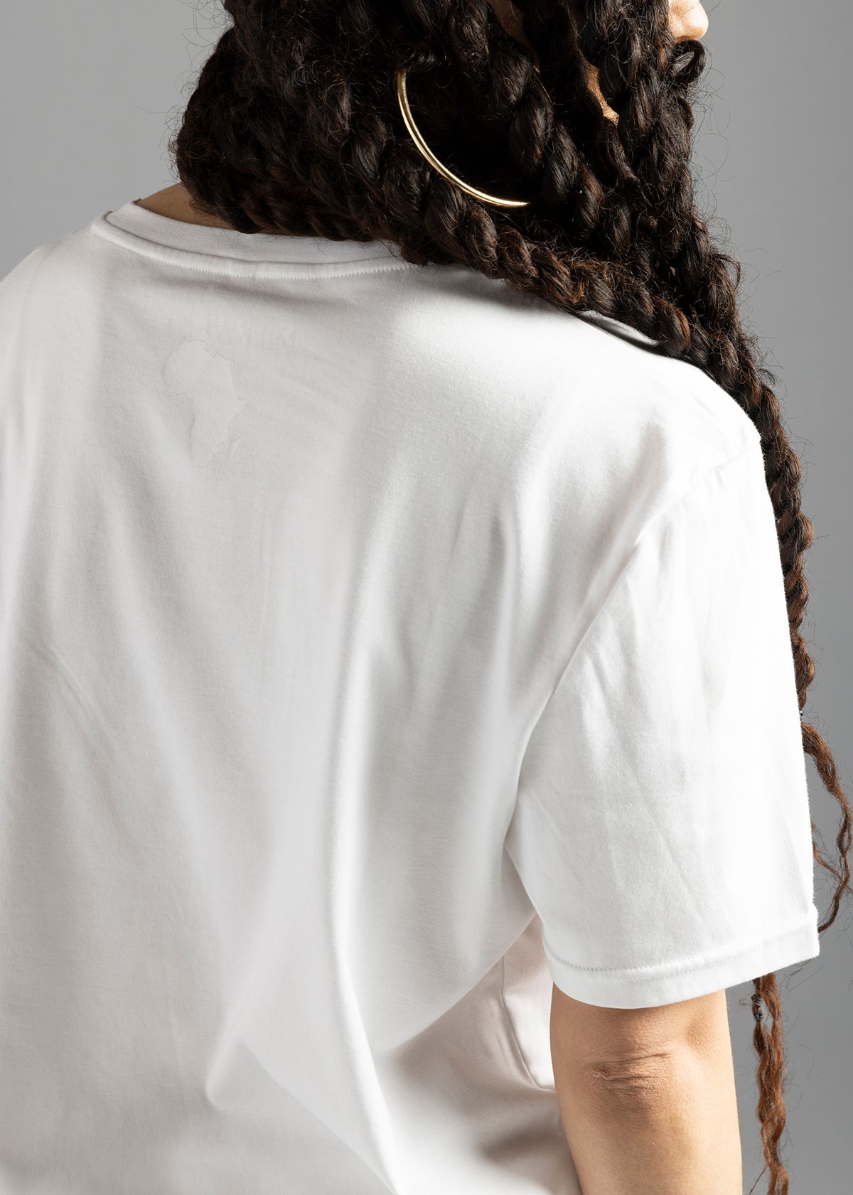 Rear close-up of the white MilkWhite Premium T-Shirt, showing the white-on-white Africa-shaped graphic beneath the neckline.
