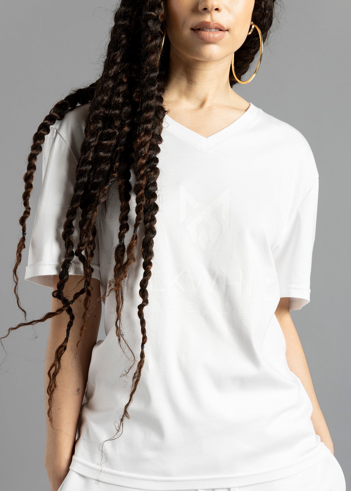 Front close-up of a model wearing the white MilkWhite Premium T-Shirt, showing the V-neck and white-on-white chest logo and lettering.