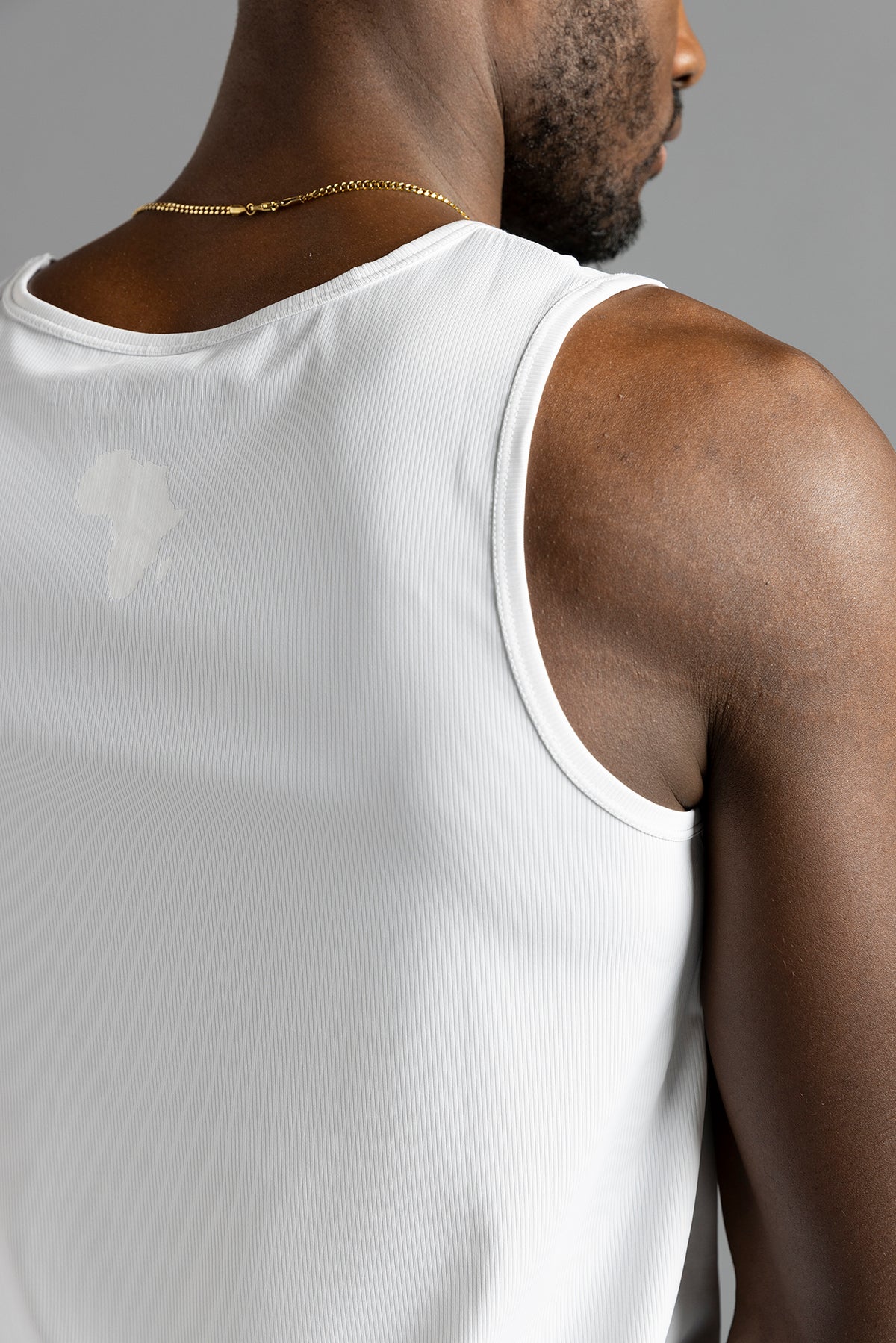 Close-up of the back shoulder of the white MilkWhite Premium Tank Top, showing ribbed texture and a tonal Africa-shaped graphic.