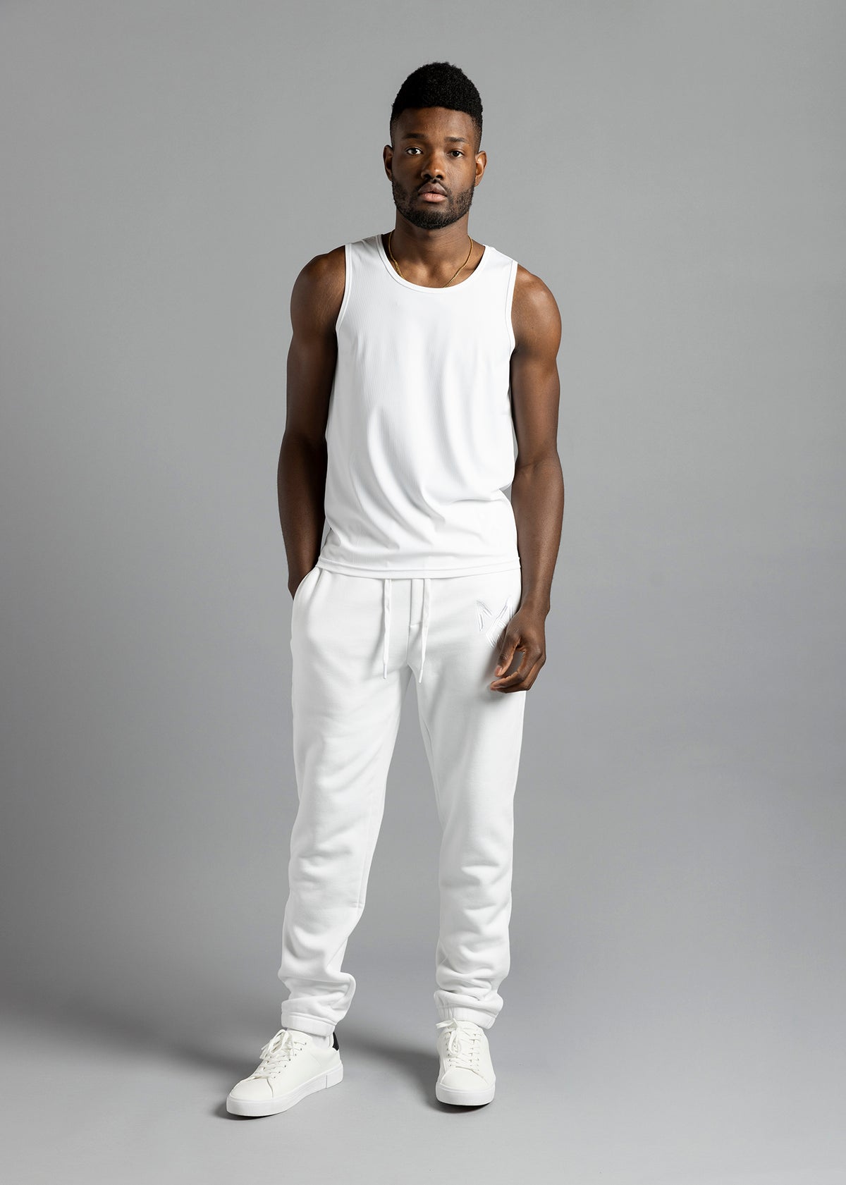 Full-length front view of a model wearing the white MilkWhite Premium Tank Top with white drawstring joggers.