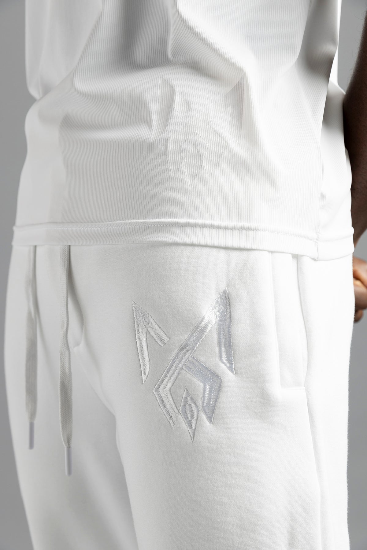 Close-up of the white MilkWhite Premium Tank Top hem and ribbed texture, worn over white joggers.