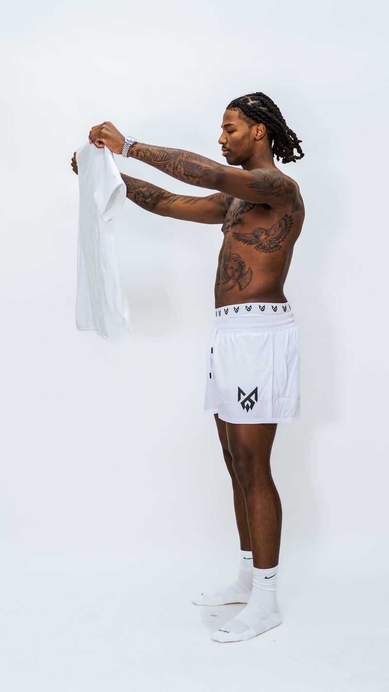 Male model wearing Milkwhite short swim trunks and underwear while holding a Milkwhite T-shirt in front of him.