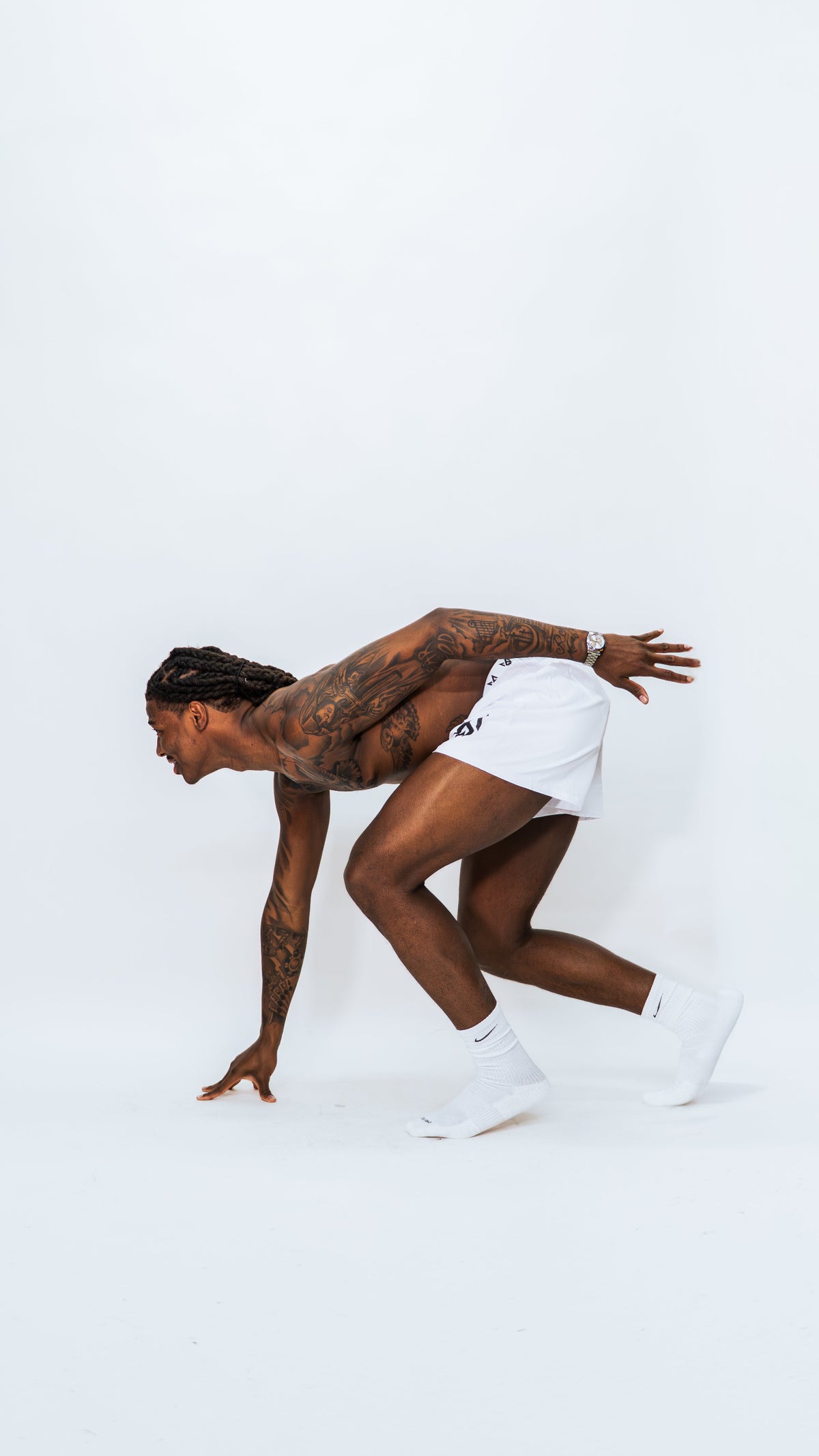 Model wearing Milkwhite Short swim trunks in an athletic sprint pose against white background. 