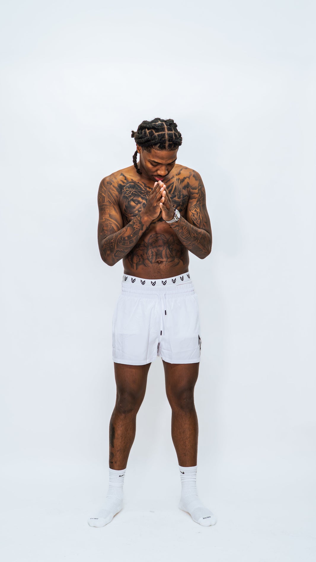 Male model wearing Milkwhite short white swim trunks against a white background.