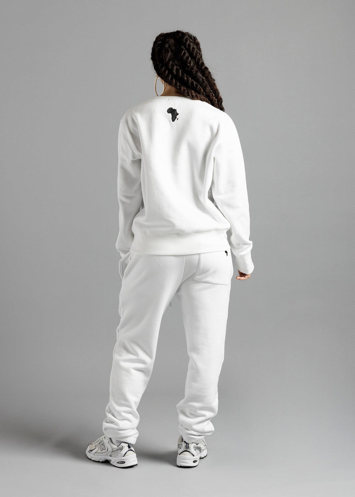 Full-length rear view of a model wearing the white Milk Essential Sweatshirt by MilkWhite, with a dark Africa-shaped graphic on the upper back.