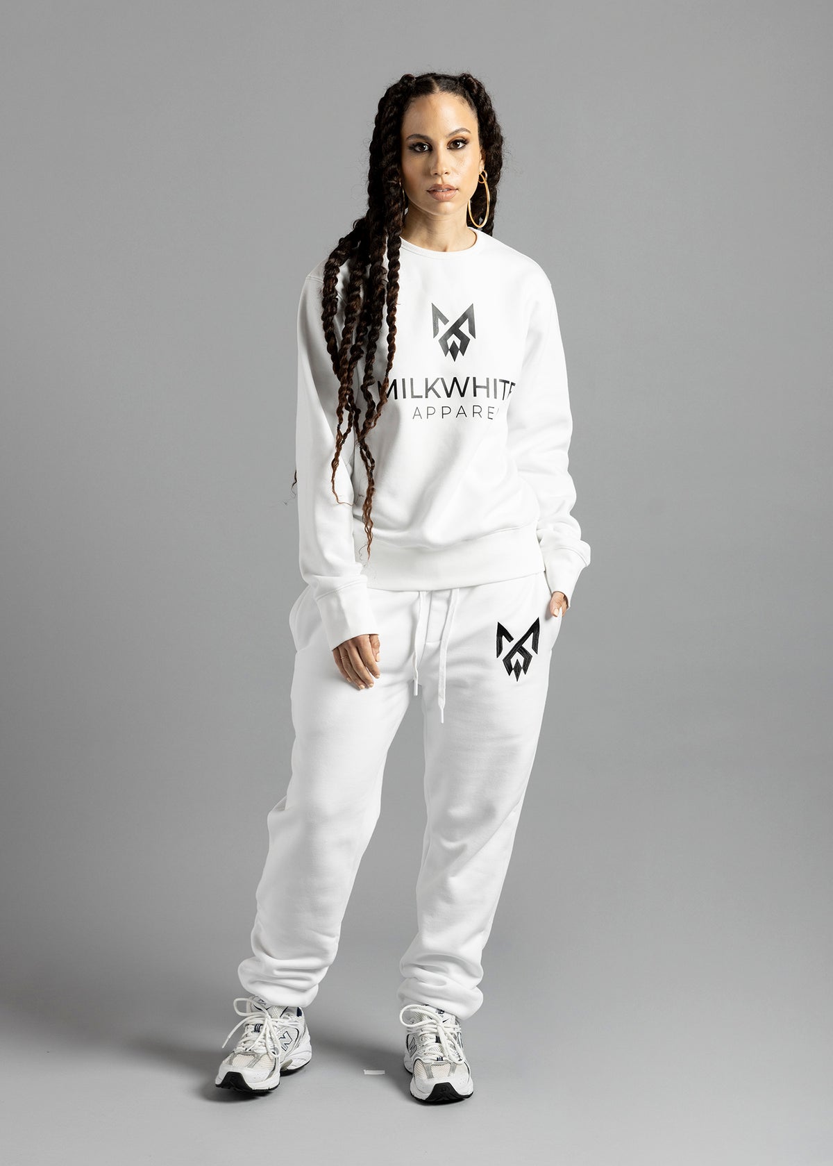 Full-length front view of a model wearing the white Milk Essential Sweatshirt by MilkWhite, with a dark chest logo and lettering.