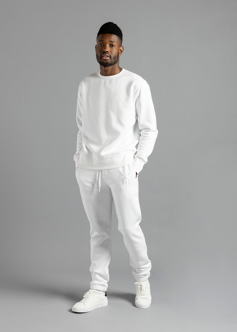 Full-length three-quarter front view of a model wearing the white Milk Essential Sweatshirt by MilkWhite, with hands in trouser pockets.