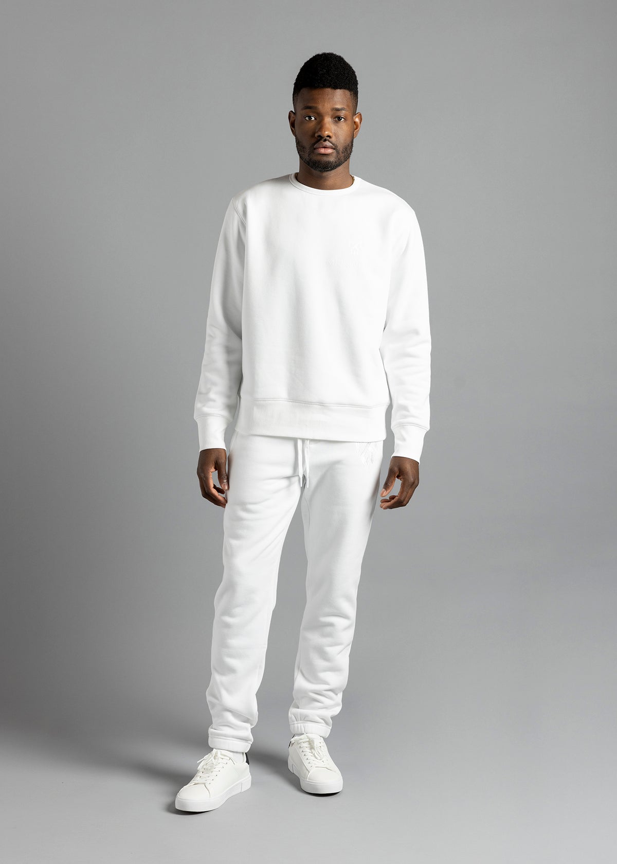 Full-length front view of a model wearing the white Milk Essential Sweatshirt by MilkWhite, showing its crew neckline, long sleeves and ribbed hem.