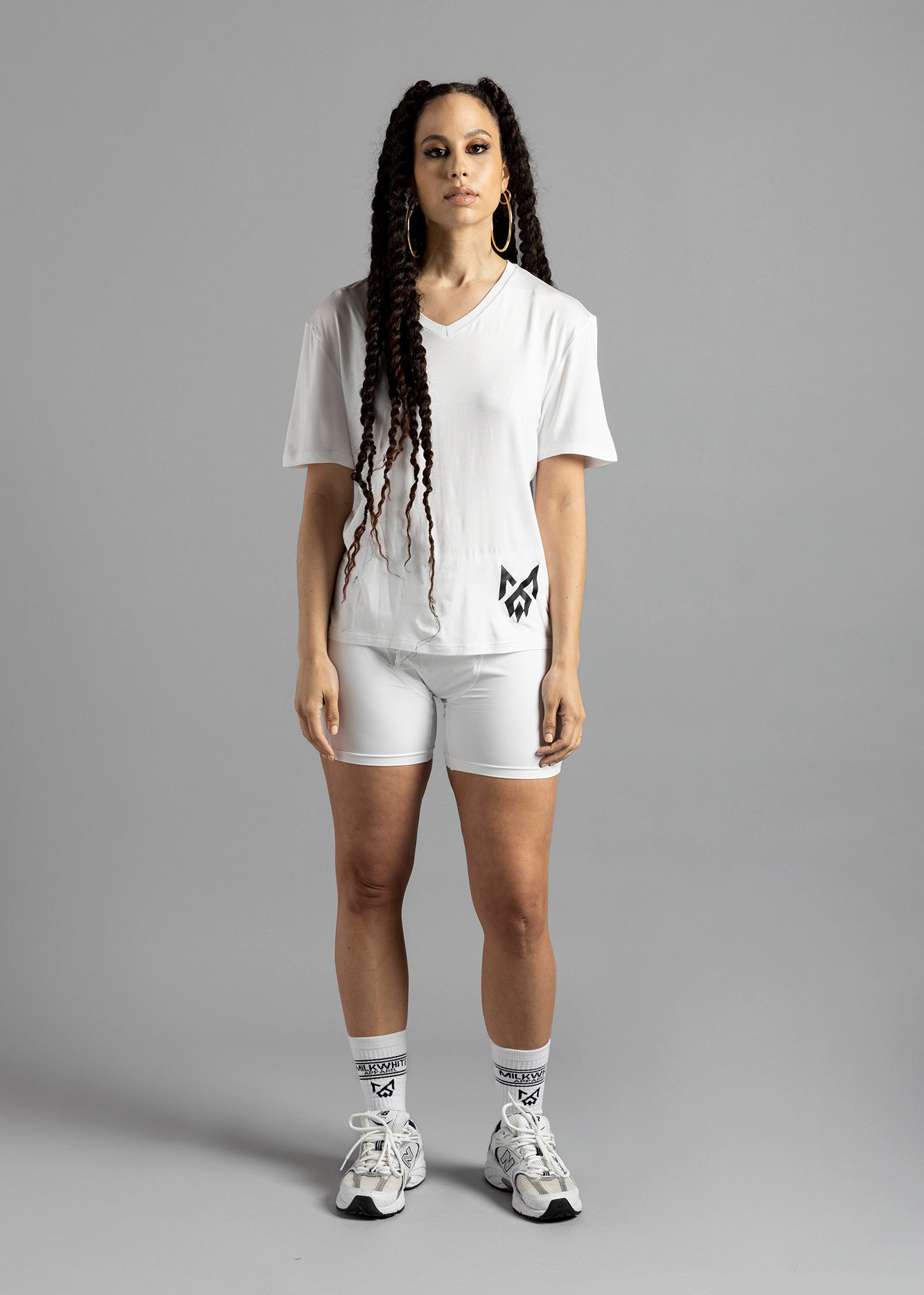 A woman wearing a white Milk Under t-shirt with logo on bottom left, MilkWhite Briefs, and MilkWhite socks.