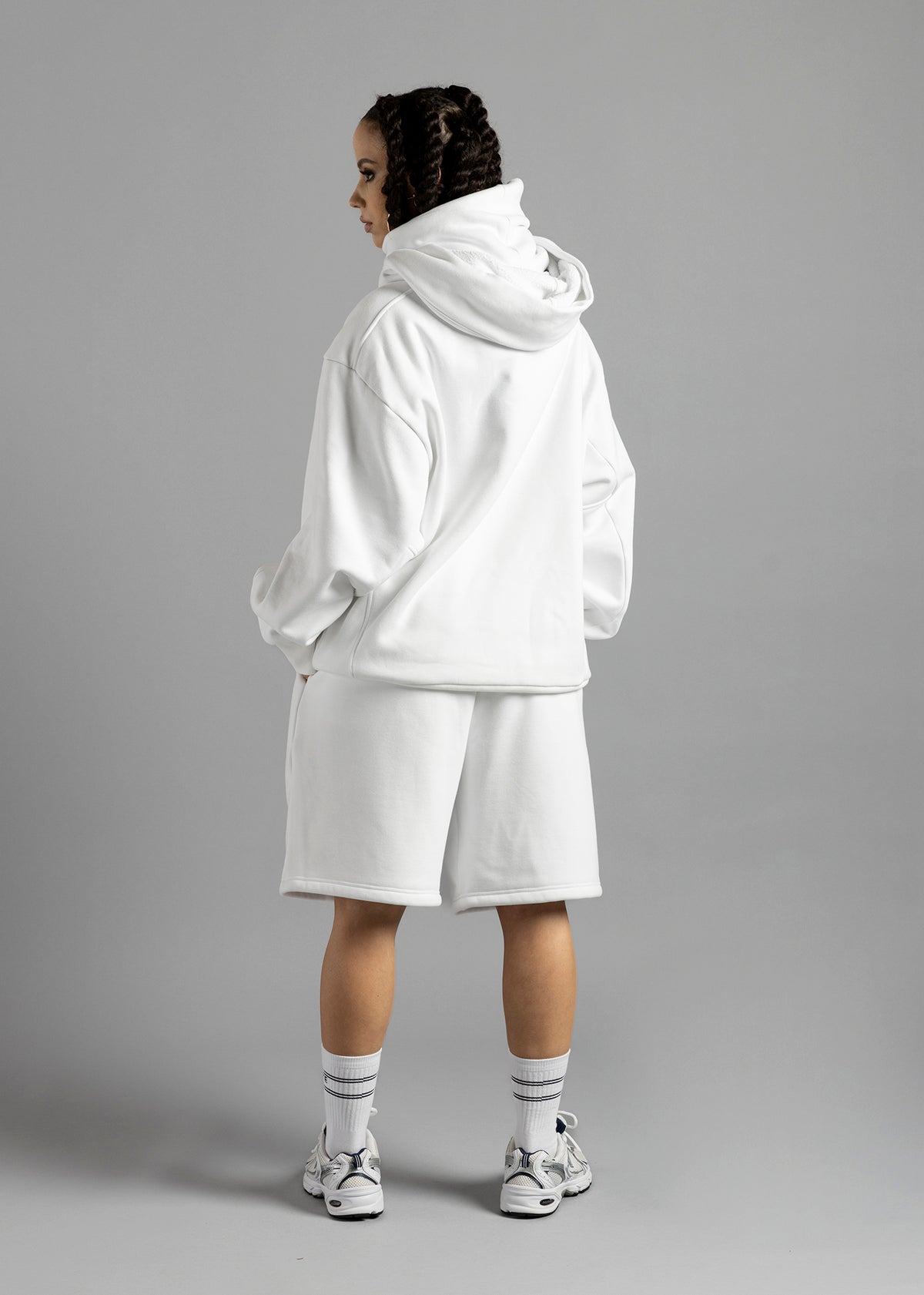 Full-length rear view of a model wearing the white Rosebud Hoodie by MilkWhite, showing the hood down and plain back.