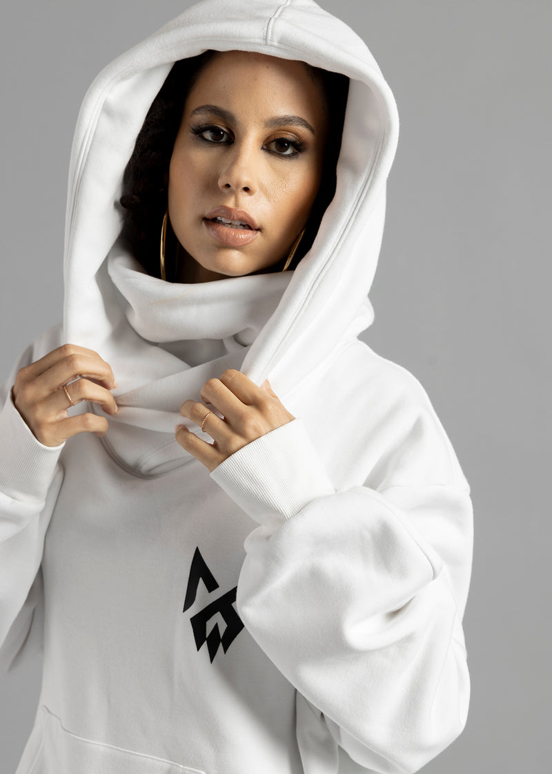 Front close-up of a model wearing the white Rosebud Hoodie by MilkWhite with the hood up and hands holding its edges.