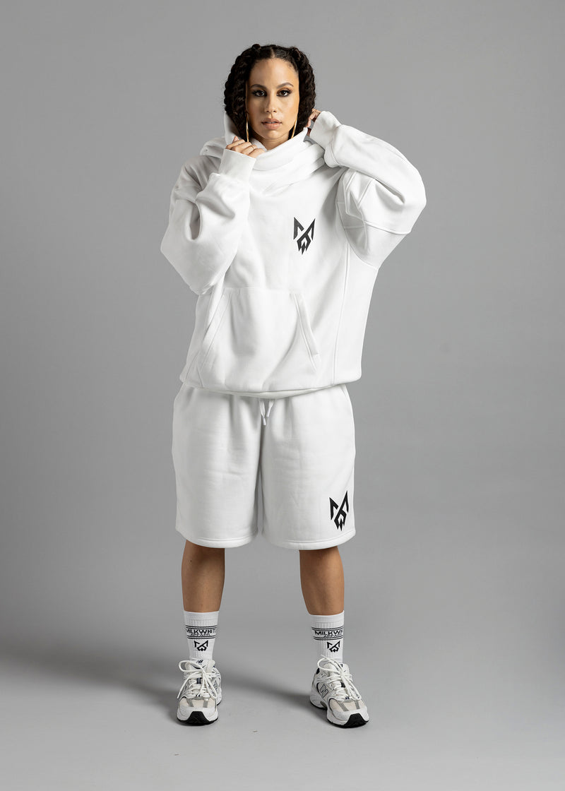 Full-length front view of a model wearing the white Rosebud Hoodie by MilkWhite, holding the draped neckline above the black chest logo.